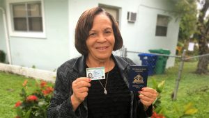 Haitian mother holding green card and passport.